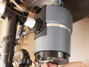 A plumber performs a garbage disposal repair service.